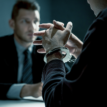 person in handcuffs talking to attorney